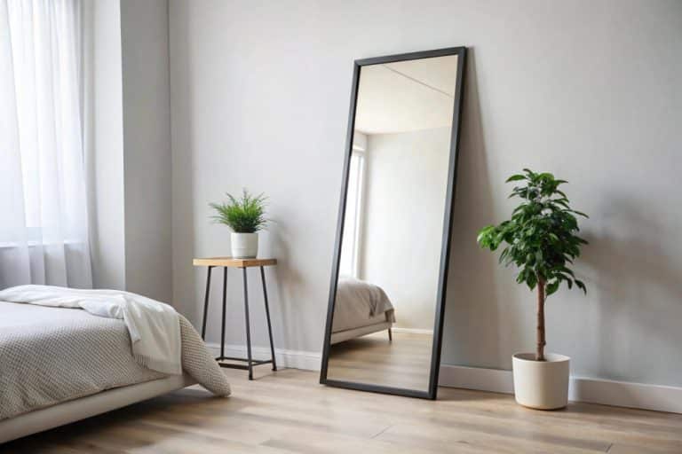 A cozy bedroom featuring a large mirror and a neatly made bed, creating a serene and inviting atmosphere.