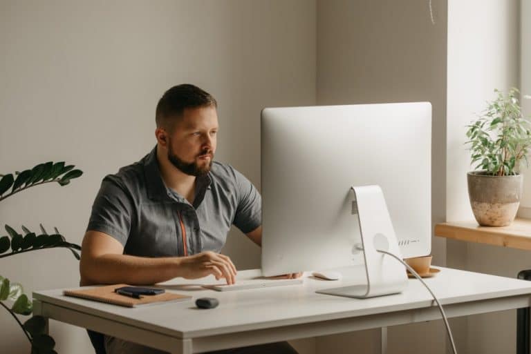 man at a desk, engaged with his computer, creating a productive atmosphere in his workspace.