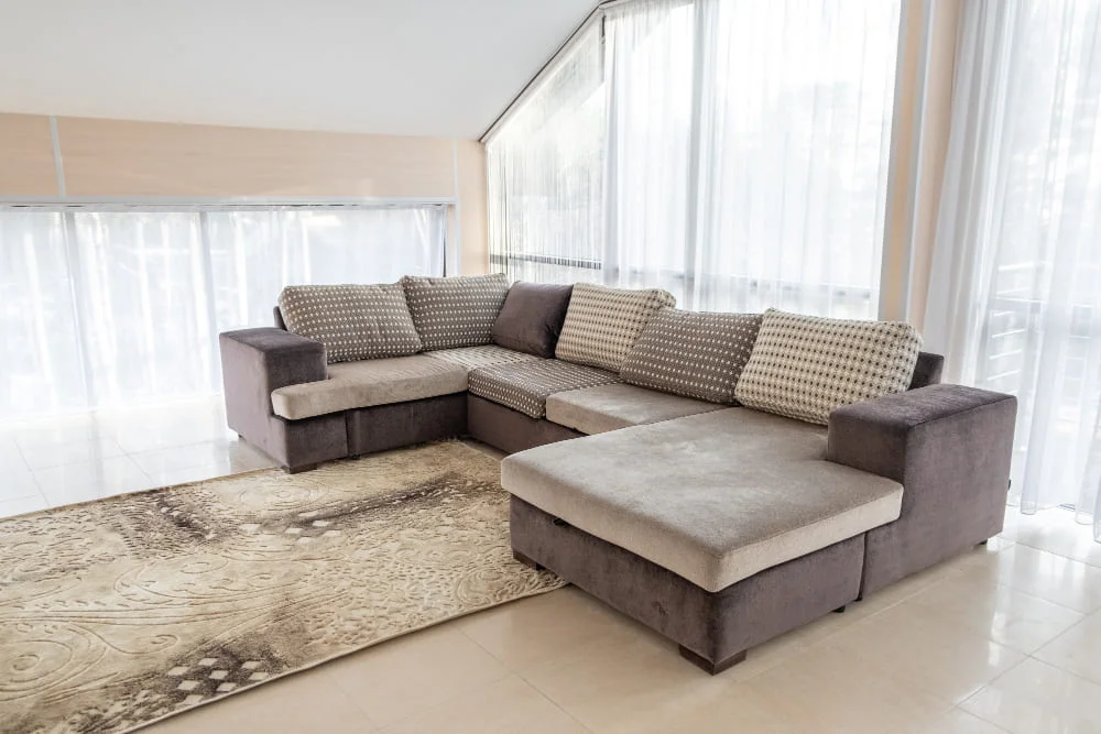 A spacious sectional couch positioned in a bright room adorned with elegant white curtains.