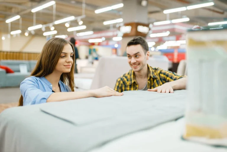 Couples are examining a bed, discussing its features and suitability for their needs.