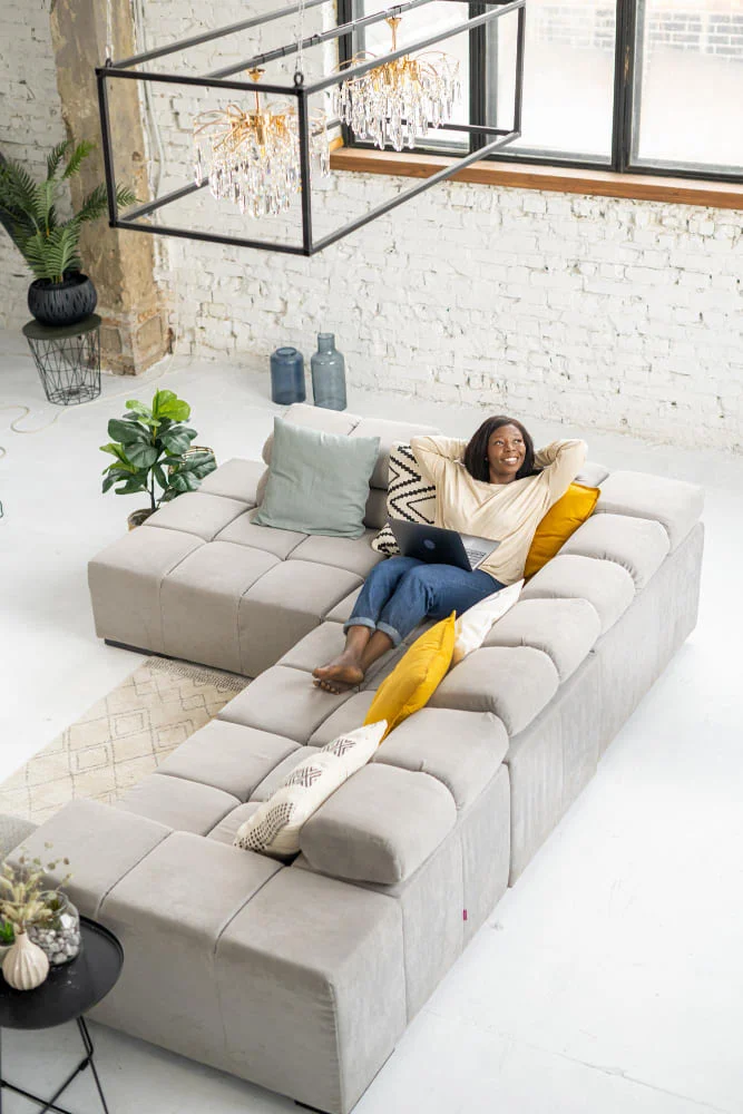 A woman relaxes on a couch in a cozy room, enjoying a moment of leisure and comfort.