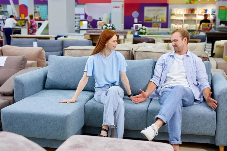 A man and woman relax on a couch in a furniture store, exploring options for their home decor.