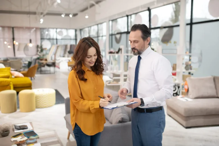 A man and woman standing together in a furniture store, examining various furniture pieces and discussing options.