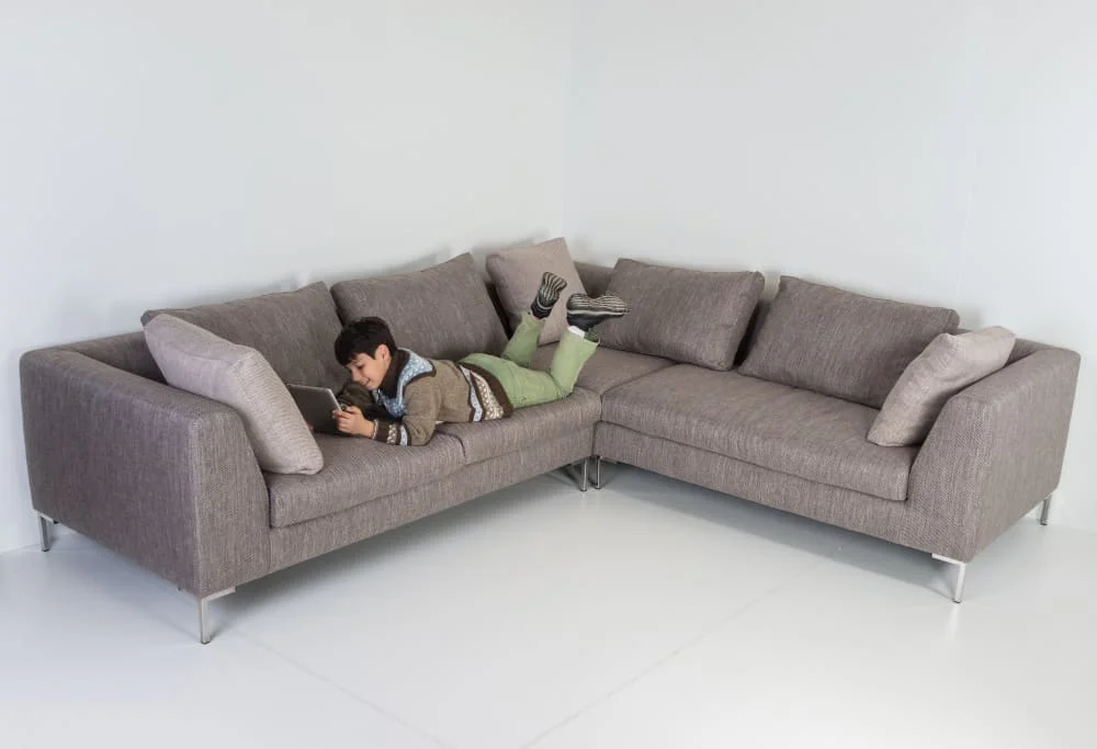 A young boy relaxes on a couch, focused on his laptop while enjoying his leisure time at home