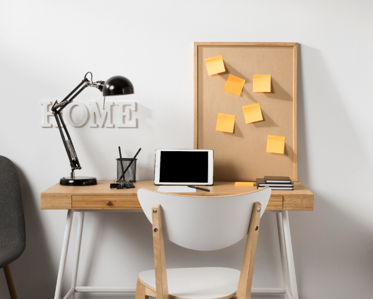 A workspace featuring a laptop on a desk, accompanied by a chair and a notepad for note-taking.