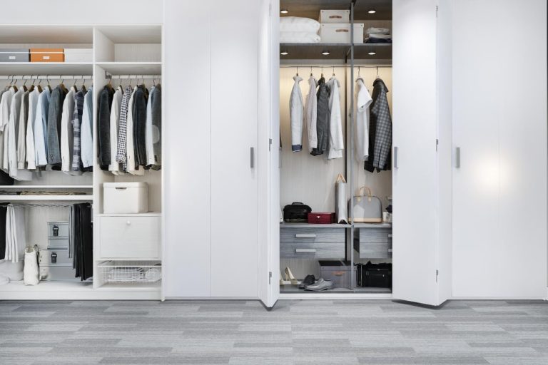 A white closet filled with neatly arranged clothes and towels, showcasing organized storage solutions.